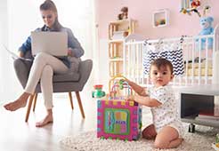 women on lap top while in the babys room.