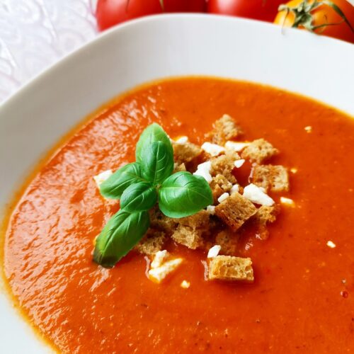 Garlic Tomato Soup in a white bowl with basil and croutons.