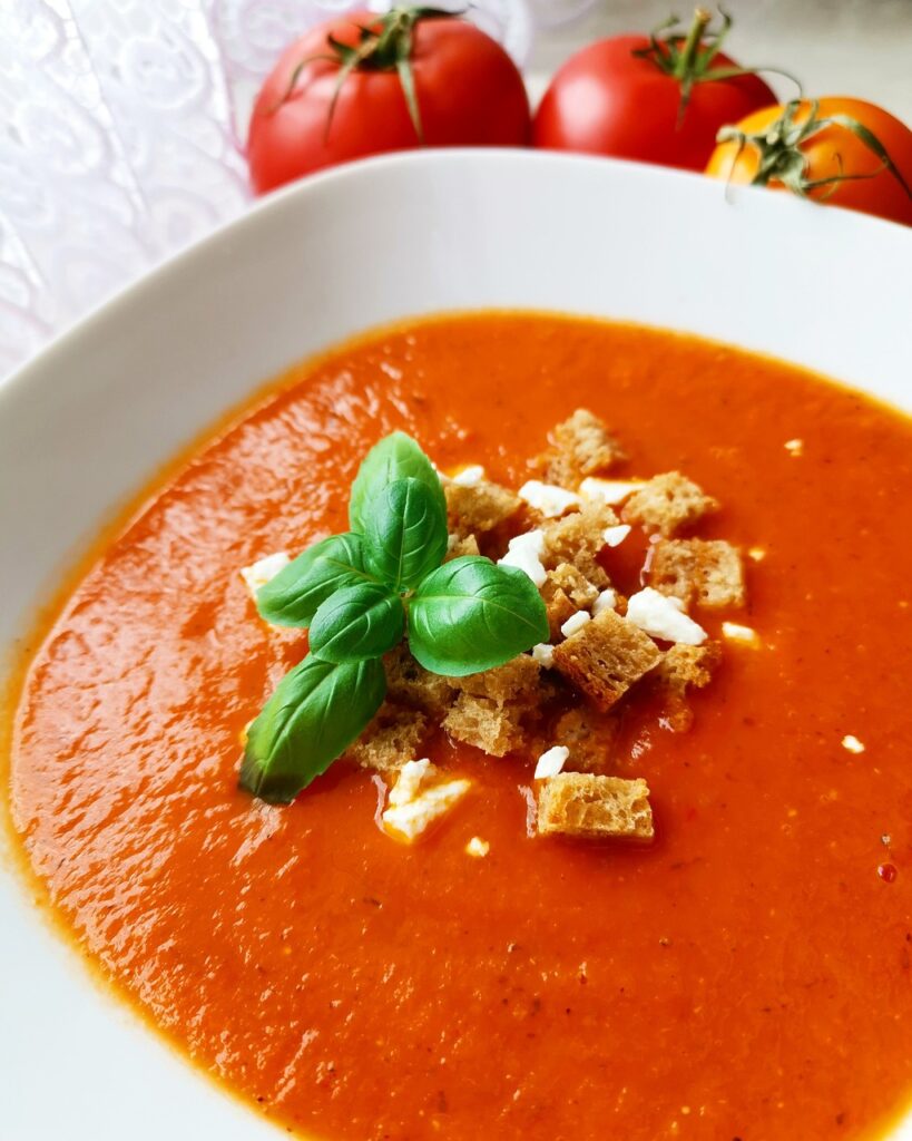 Garlic Tomato Soup in a white bowl with basil and croutons.